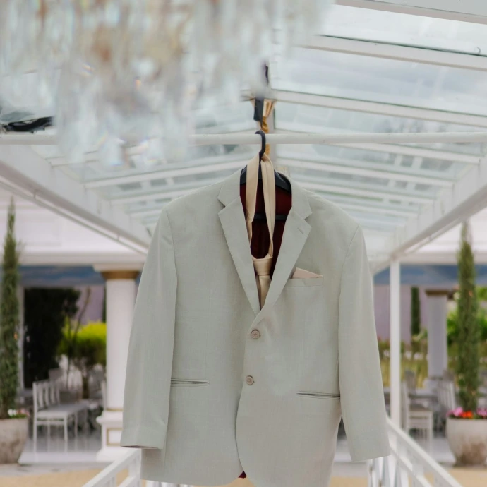 A light-colored suit jacket with tie hanging outdoors.